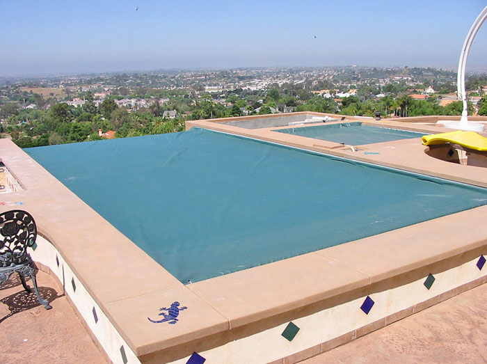 Vanishing edge pool with COVERSTAR Safety Cover in forest green.